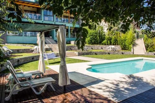 una piscina con 2 sillas y una sombrilla y una piscina en La Veleta Apart en San Antonio de Arredondo