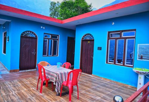 a blue house with a table and chairs on a deck at Shankara Homestay in Chamoli
