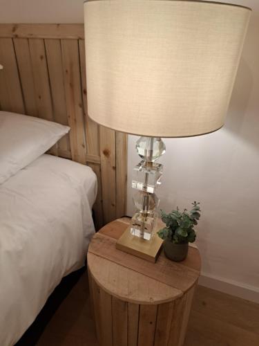 a lamp on a wooden table next to a bed at Hôtel Le Cottage de Sophie in Valernes