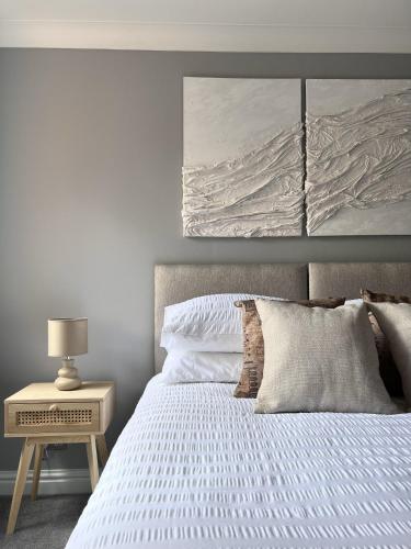 a bedroom with a white bed with a nightstand and a painting at Franklin Suite - Reading City Centre - Free Parking - Close to Station in Reading