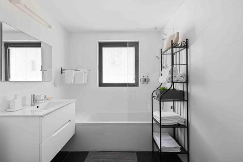 a white bathroom with a sink and a towel rack at Ambassador apartment+parking in Tel Aviv