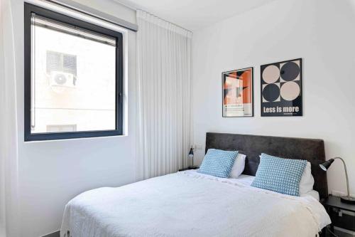 Un dormitorio con una cama con almohadas azules y una ventana en Ambassador apartment+parking, en Tel Aviv
