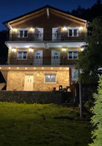 a large house with a balcony at night at Bujtina Brahim Selimaj in Valbonë