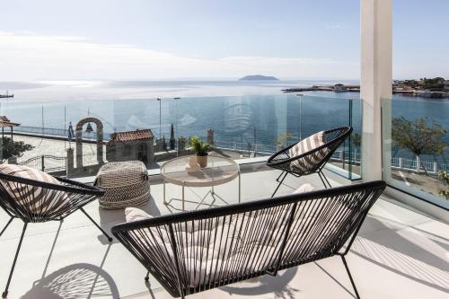 a balcony with chairs and a table and the ocean at Nōema Premium Stay in Neos Marmaras
