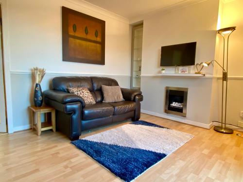 a leather couch in a living room with a fireplace at Cosy 2 bedroom home with free parking near city in Edinburgh
