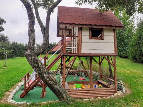 uma casa na árvore com um parque infantil num campo em Pokoje Na Brzegu 