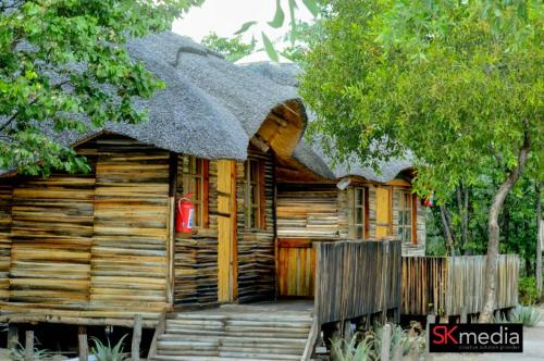 Cabaña de madera con techo de paja y porche en Mokoka Rest Camp, en Nata