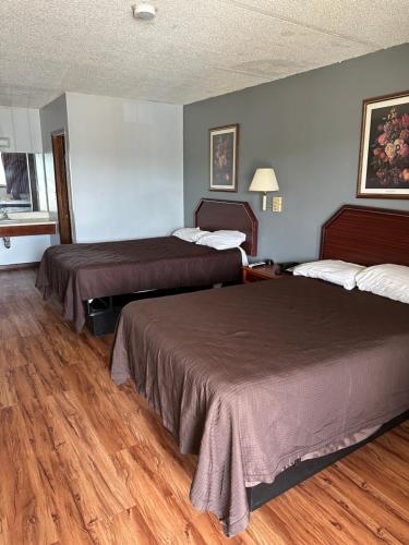 two beds in a hotel room with wood floors at Budget Inn-Gadsden in Gadsden