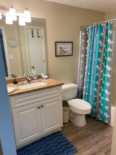 y baño con lavabo, aseo y espejo. en Shoalwater 704 en Orange Beach