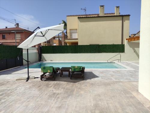 Casa Empordà con piscina exclusiva في Báscara: مسبح مع كرسيين ومظلة بيضاء