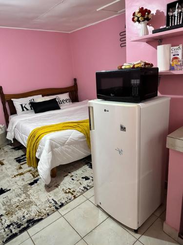 1 dormitorio con 1 cama y nevera pequeña en Ruth's Studio - Kericho, en Kericho