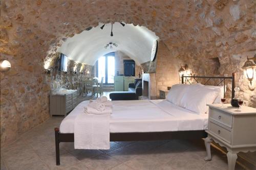 ein Schlafzimmer mit einem großen Bett in einer Steinmauer in der Unterkunft Olga's House in Neon Oitilon