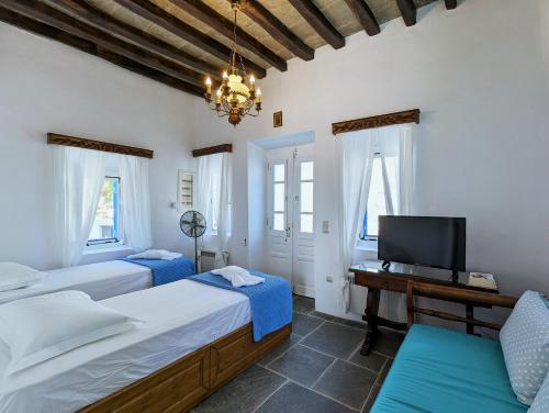1 dormitorio con 2 camas, TV y escritorio en Thavma in Sifnos en Apollonia