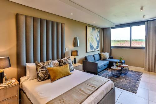 a bedroom with a bed and a couch and a chair at Zimbali Lakes Boulevard Suite 134 in Sheffield Beach