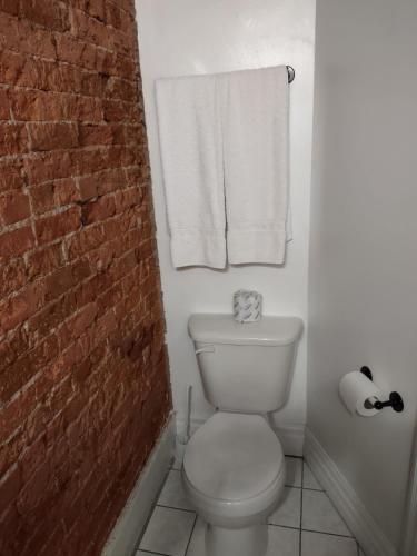 a bathroom with a white toilet and a brick wall at The King George Inn in Cobourg