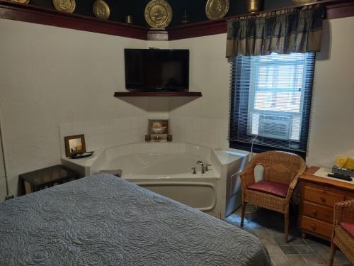 a bedroom with a tub and a bed and a television at The King George Inn in Cobourg