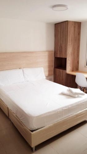 1 dormitorio con 1 cama grande con sábanas blancas en Aw Hotel Pasarela Real, en Cali