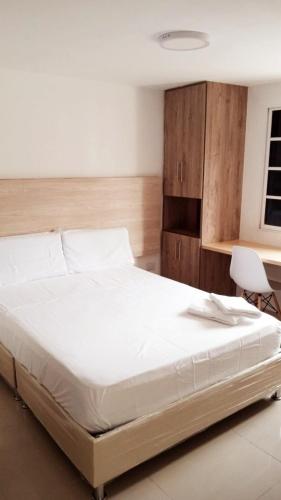 1 dormitorio con 1 cama blanca, escritorio y silla en Aw Hotel Pasarela Real, en Cali