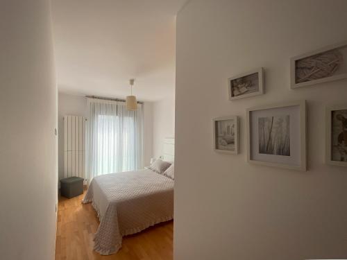 ein weißes Schlafzimmer mit einem Bett und Bildern an der Wand in der Unterkunft Garatuxa Home in Bueu