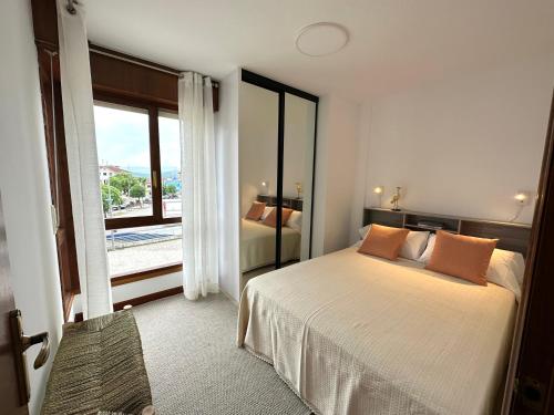 een slaapkamer met een bed en een groot raam bij Apartamento El Olivo in Noja