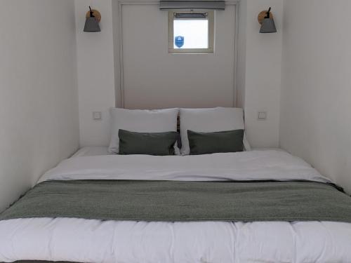 una camera da letto con un letto con lenzuola bianche e cuscini verdi di Amsterdam City Oasis ad Amsterdam
