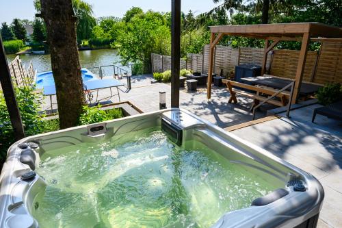 a jacuzzi tub on a patio with a table and a picnic table at Körös-parti Terasz Vendégház in Békésszentandrás