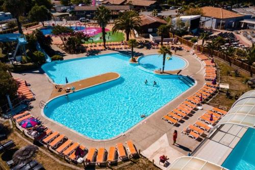 Elle offre une vue sur la grande piscine bordée de chaises. dans l'établissement Mobil home Lège Cap Ferret Camping 4 étoiles Les Viviers, à Lège-Cap-Ferret