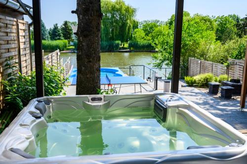 a jacuzzi tub in a backyard with a tree at Körös-parti Terasz Vendégház in Békésszentandrás