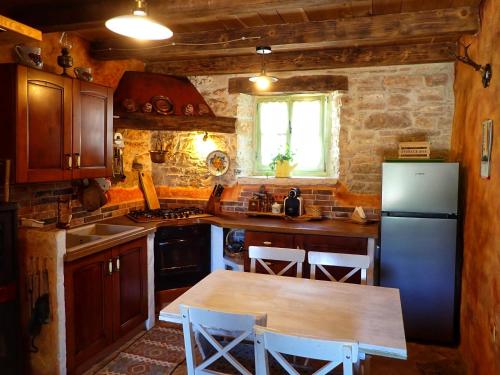 a kitchen with a refrigerator and a table with chairs at Cottage al Merlo Olivo in Buje