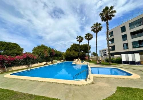 una gran piscina azul con palmeras y un edificio en Apartament Blanca, en La Mata
