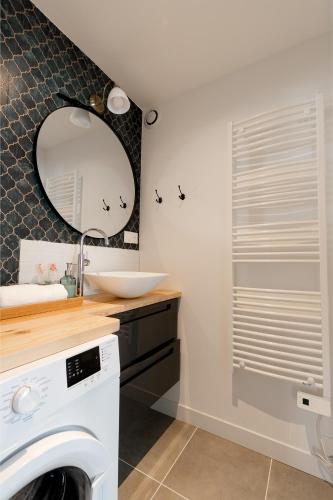 une salle de bain avec un lavabo et une machine à laver dans l'établissement Logement 2 chambres spacieux Lit King Verdun parking gratuit, à Valence