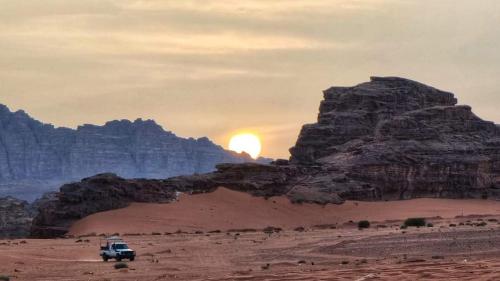 Ein Laster in der Wüste mit Sonnenuntergang hinter den Bergen. in der Unterkunft Areen camp, Wadi Rum in Wadi Rum