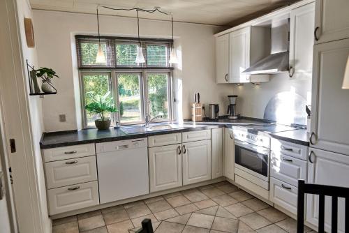 een keuken met witte kasten, een wastafel en een raam bij Modern vacation Home - Close to sea and nature. in Hejls