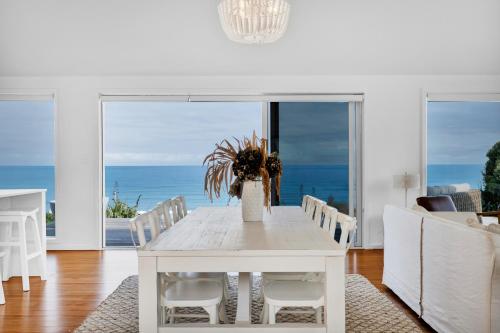 ein weißes Esszimmer mit einem Tisch und Meerblick in der Unterkunft MOKAU BEACH HOUSE in Mokau