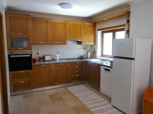 - une cuisine avec des placards en bois et un réfrigérateur blanc dans l'établissement Casa das Andorinhas, à Lourinhã