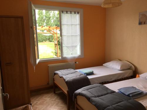 two beds in a room with a window at Cottage le petit Tôt in Barneville-Carteret