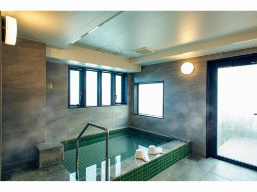 a bathroom with a bath tub with a window at Kuretake Inn Premium Tajimi Ekimae in Tajimi