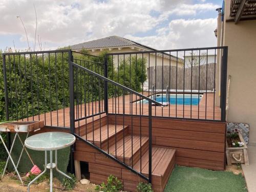 a deck with a swimming pool and a fence at צימר מול השקיעה in Retamim