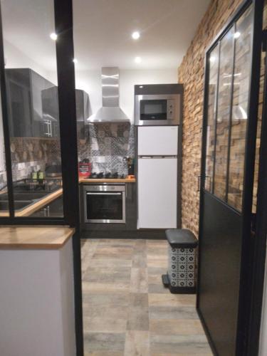 Il comprend une cuisine équipée d'un réfrigérateur blanc et d'une cuisinière. dans l'établissement L'atelier, à Foissac