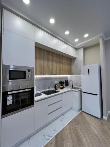 cocina con armarios blancos y nevera en ЖК - 4 YOU - Nomaden- 3, en Almaty