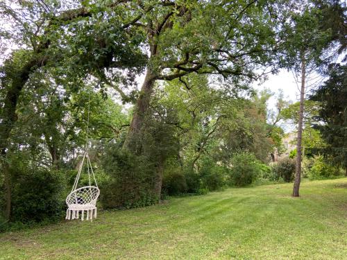 a white swing hanging from a tree in a yard at Domaine de Lanis - Maison d'hôtes avec parc et piscine in Castelnaudary