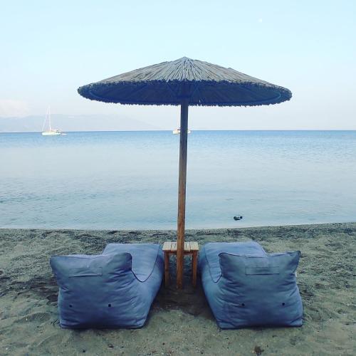 two blue chairs under an umbrella on the beach at Nereides Seaside Apartments in Marathokampos