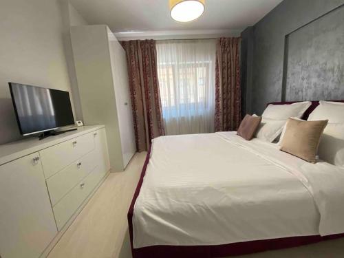 1 dormitorio con 1 cama blanca grande y TV de pantalla plana en Dem ‘LuxuryApartmens en Râmnicu Vâlcea
