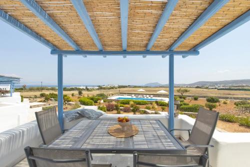 a patio with a table and chairs and a view of the ocean at White Cliff 4 - Cycladic Home in Ambelas