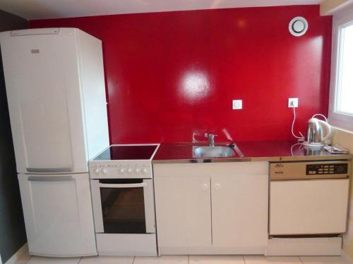 a red kitchen with a sink and a refrigerator at Gite Au Cheval D'or in La Meilleraie-Tillay