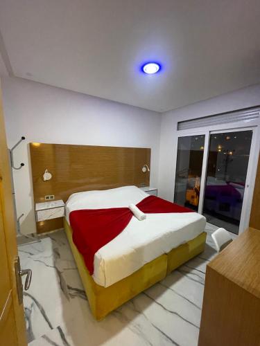 a bedroom with a large bed with a red blanket at appart hotel puerto marino in Al Hoceïma