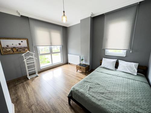 a bedroom with a bed and two windows and a ladder at Doğanın Kalbindeki Eviniz-9 Kişi in Gemlik