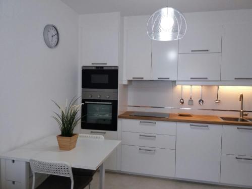 uma cozinha com armários brancos, uma mesa e um relógio em La casita de la playa em Ribeira