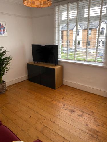 a living room with a flat screen tv and two windows at Coastal haven in Portstewart