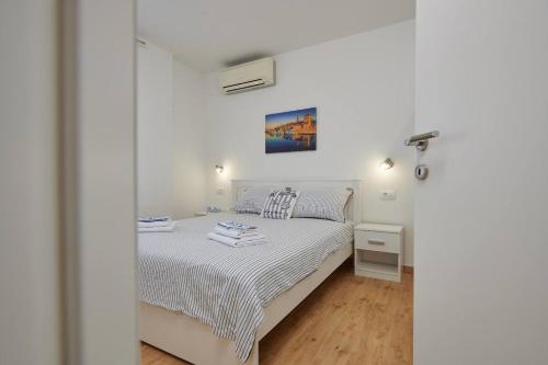 um quarto branco com uma cama e uma janela em Trau em Trogir